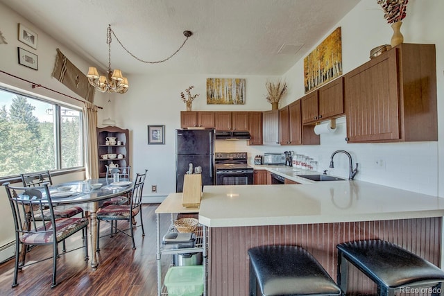 9800 Ryan Gulch Rd Unit A-101, Silverthorne, CO 80498 - kitchen featuring black appliances, a peninsula, light countertops, dark wood-style floors, and a chandelier
