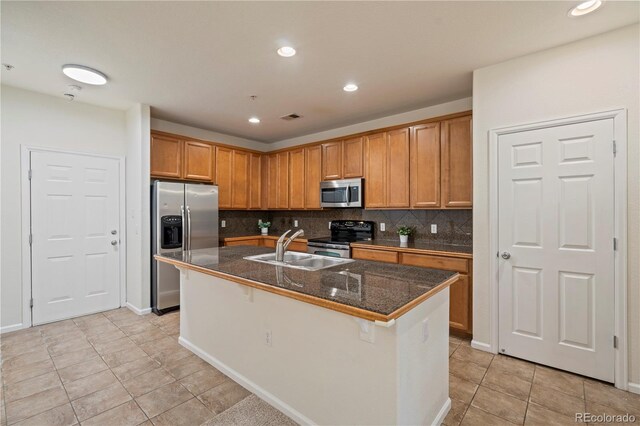 9907 Martin Luther King Blvd Unit 103, Denver, CO 80238 - kitchen featuring appliances with stainless steel finishes, a sink, light tile patterned floors, decorative backsplash, and a center island with sink