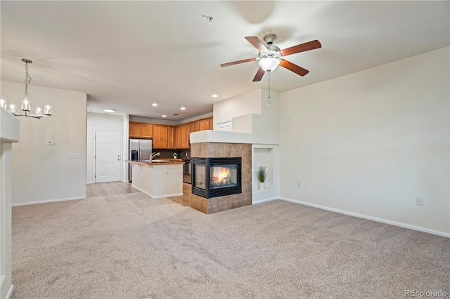 9907 Martin Luther King Blvd Unit 103, Denver, CO 80238 - unfurnished living room featuring a chandelier, light colored carpet, a tile fireplace, a ceiling fan, and baseboards