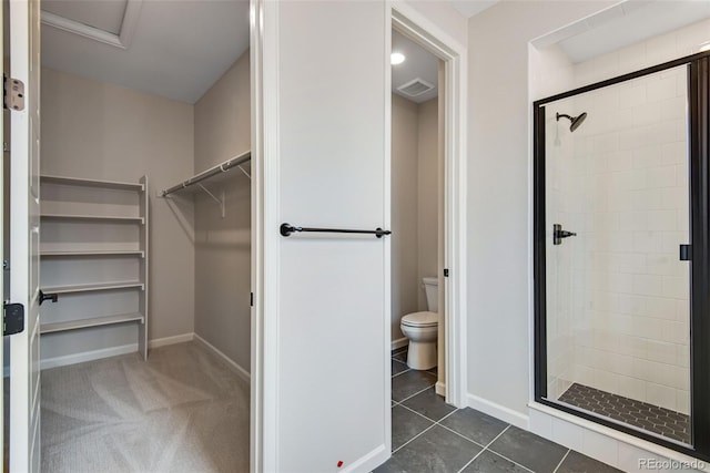 bathroom with toilet, a shower with shower door, and tile patterned flooring