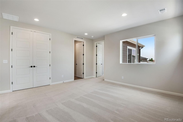 unfurnished bedroom featuring light carpet and a closet