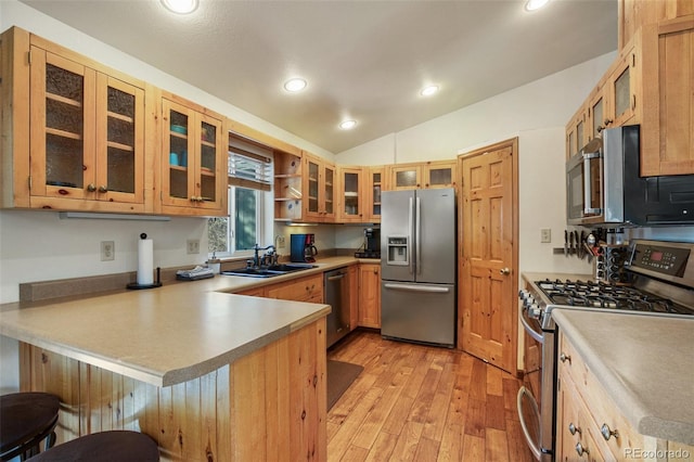 kitchen featuring sink, a breakfast bar area, vaulted ceiling, kitchen peninsula, and stainless steel appliances