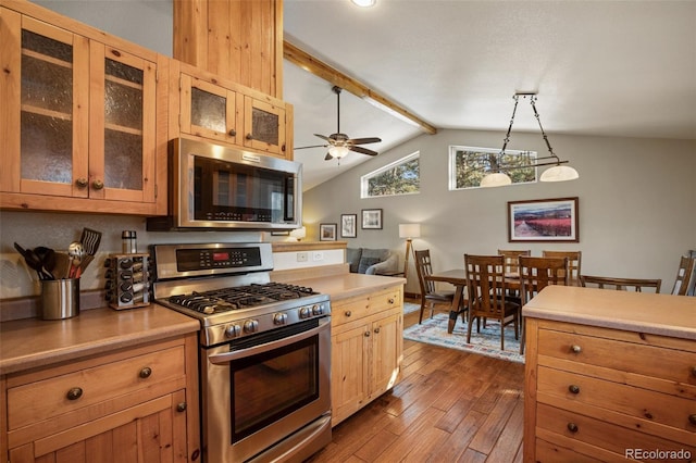 kitchen with dark hardwood / wood-style floors, vaulted ceiling with beams, hanging light fixtures, ceiling fan, and stainless steel appliances