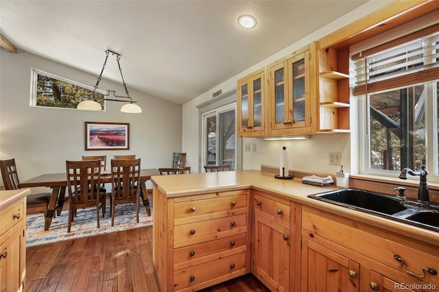 kitchen featuring lofted ceiling, sink, dark hardwood / wood-style flooring, kitchen peninsula, and pendant lighting