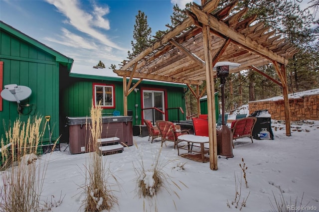 snow covered patio with a hot tub and a pergola