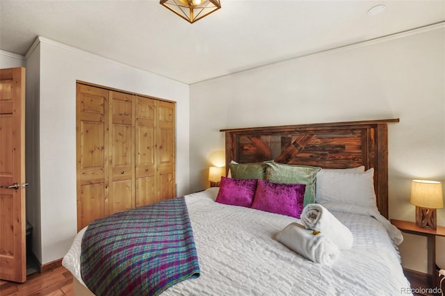 bedroom featuring wood-type flooring, ornamental molding, and a closet