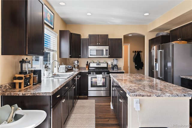 kitchen featuring dark brown cabinetry, a center island, appliances with stainless steel finishes, and a sink