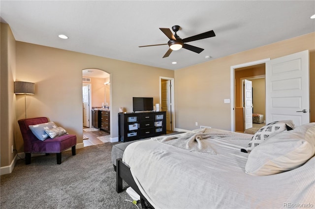 carpeted bedroom with ensuite bath, recessed lighting, arched walkways, baseboards, and ceiling fan