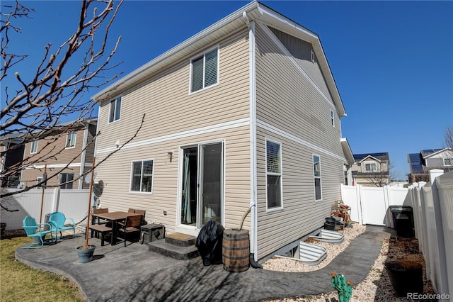 back of property with entry steps, a patio area, and a fenced backyard