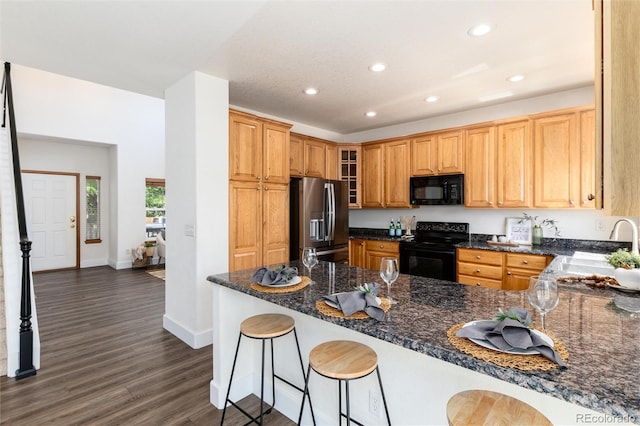 9610 S Dover Way, Littleton, CO 80127 - kitchen with black appliances, recessed lighting, dark wood-style floors, a peninsula, and glass insert cabinets