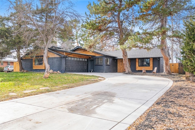 view of front of home featuring driveway, a garage, brick siding, fence, and a front yard