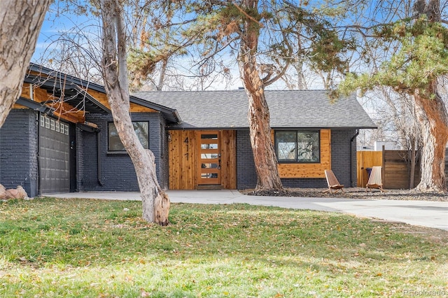 view of front of house featuring a shingled roof, a front yard, and brick siding