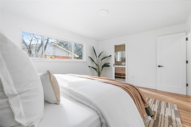 bedroom featuring connected bathroom, baseboards, and wood finished floors