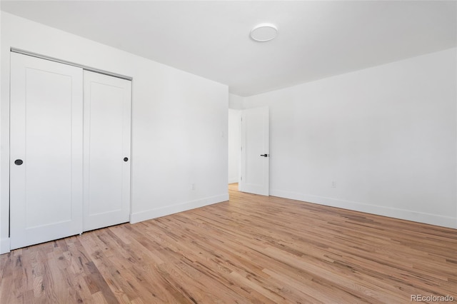 unfurnished bedroom with light wood-type flooring, baseboards, and a closet