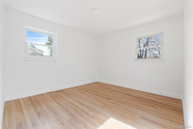 empty room with wood finished floors, visible vents, and baseboards