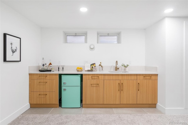 interior space with freestanding refrigerator, indoor wet bar, a sink, and light tile patterned floors