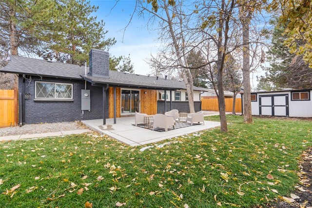 rear view of house featuring a storage unit, a lawn, a patio area, fence, and an outdoor structure