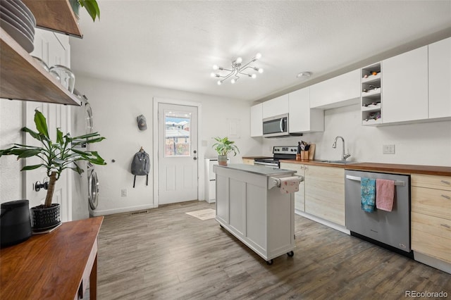 kitchen with white cabinets, stainless steel appliances, a chandelier, and sink