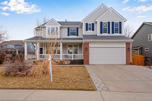 traditional-style house featuring driveway, a garage, a porch, and brick siding