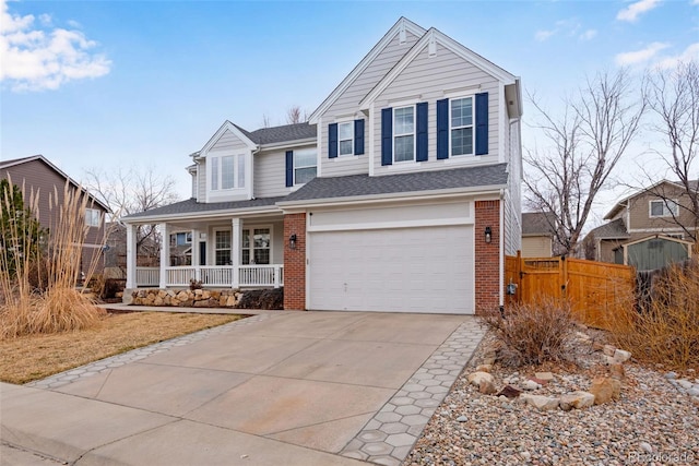 traditional home with brick siding, a porch, concrete driveway, fence, and a garage