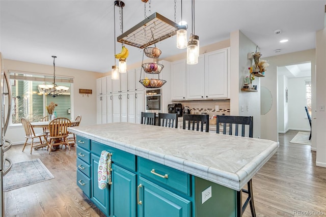 kitchen featuring a kitchen island, a kitchen breakfast bar, white cabinets, blue cabinetry, and light wood-type flooring