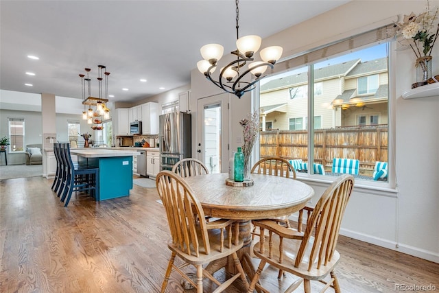 dining room with a chandelier, light wood finished floors, recessed lighting, and baseboards