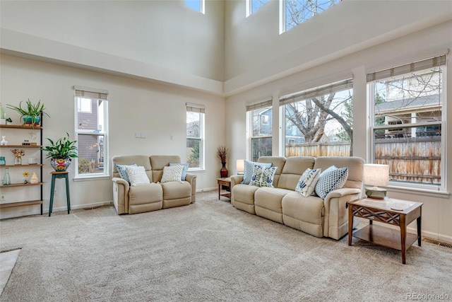 carpeted living room featuring a high ceiling, visible vents, and baseboards