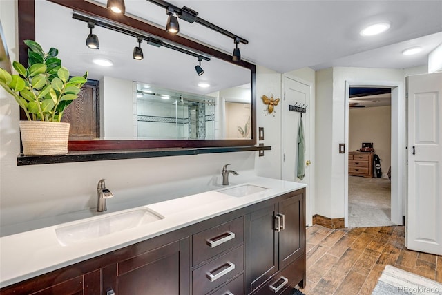 bathroom featuring wood tiled floor, a sink, a shower stall, and double vanity