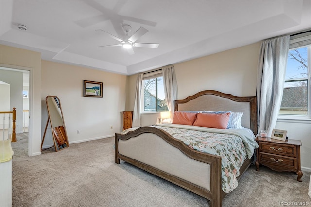 carpeted bedroom featuring a tray ceiling, a ceiling fan, and baseboards