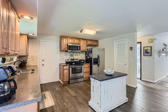 6212 S Ash Cir W, Centennial, CO 80121 - kitchen featuring appliances with stainless steel finishes, dark countertops, dark wood-style floors, backsplash, and a center island