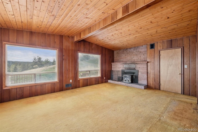 150 Apache Trl, Woodland Park, CO 80863 - unfurnished living room featuring wooden ceiling, a wood stove, wood walls, and carpet floors