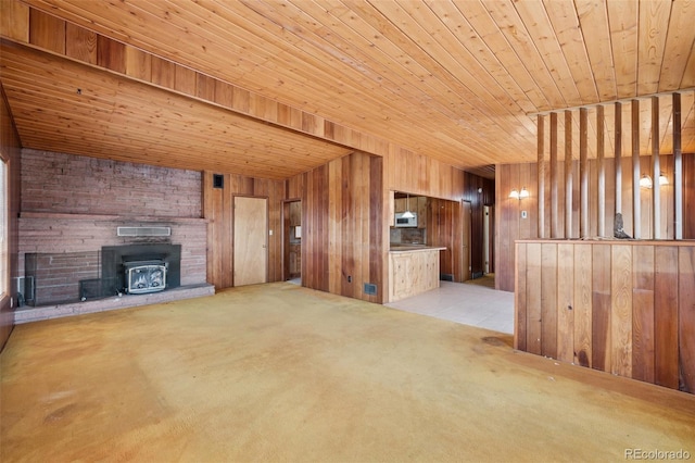 150 Apache Trl, Woodland Park, CO 80863 - unfurnished living room featuring wooden ceiling, wooden walls, light colored carpet, and a wood stove