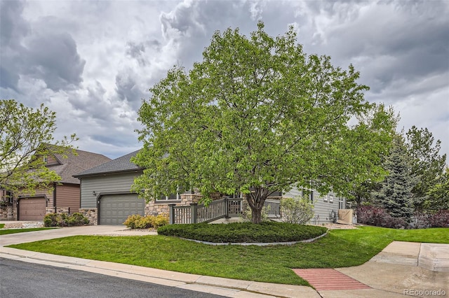 view of property hidden behind natural elements featuring a front lawn and a garage