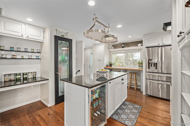 kitchen with a center island, wine cooler, wood-type flooring, white cabinetry, and stainless steel fridge