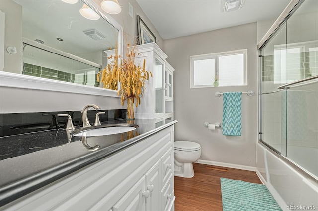 full bathroom featuring enclosed tub / shower combo, toilet, oversized vanity, and hardwood / wood-style floors