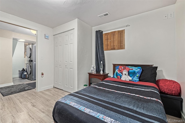 bedroom with light hardwood / wood-style floors and stacked washing maching and dryer