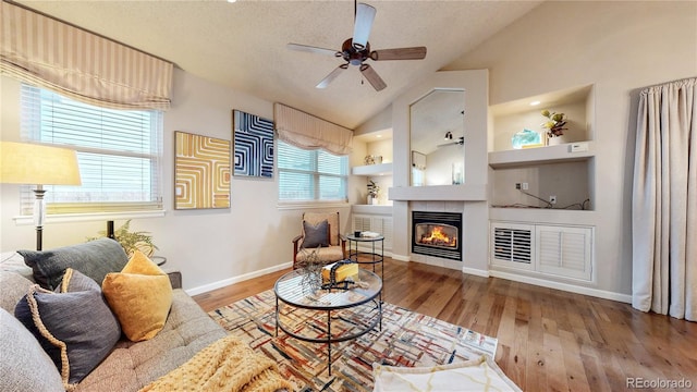 2266 S Kenton St, Aurora, CO 80014 - living area with a textured ceiling, wood finished floors, built in features, vaulted ceiling, and a tiled fireplace