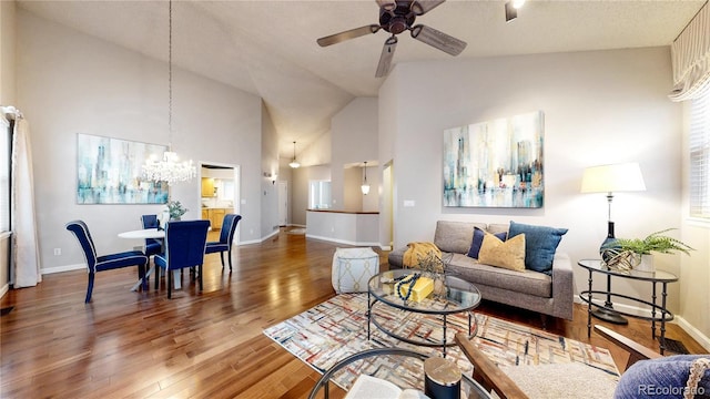 2266 S Kenton St, Aurora, CO 80014 - living room featuring ceiling fan with notable chandelier, high vaulted ceiling, wood finished floors, and baseboards