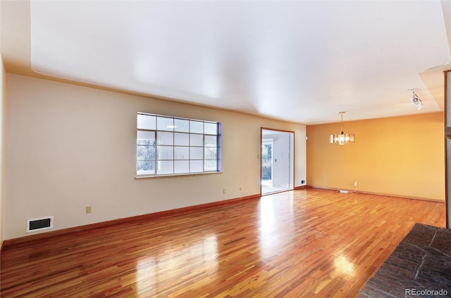 unfurnished room with hardwood / wood-style floors and a notable chandelier