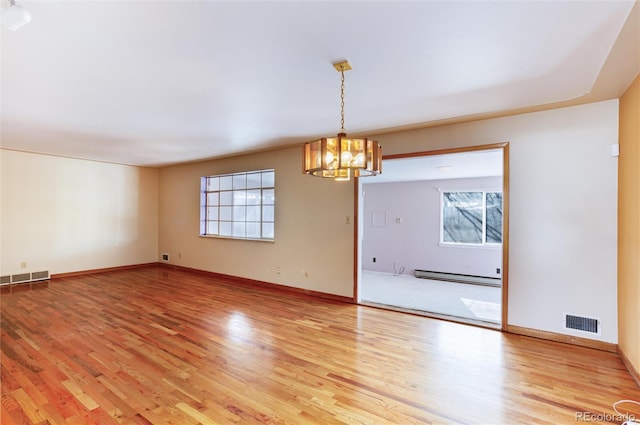 unfurnished room featuring baseboard heating, a notable chandelier, and hardwood / wood-style flooring