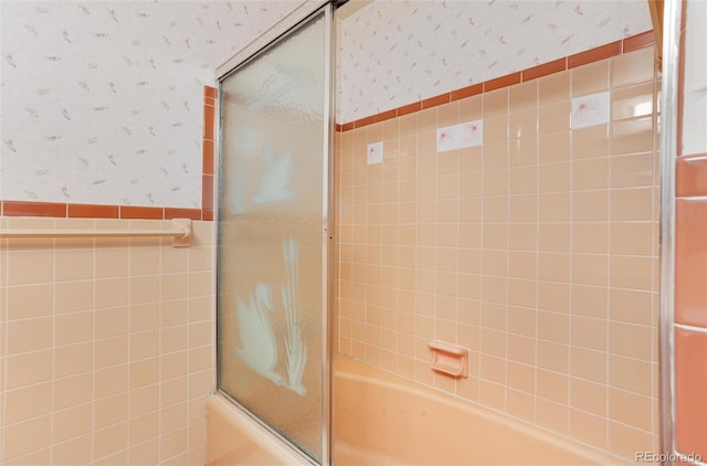 bathroom featuring bath / shower combo with glass door and tile walls