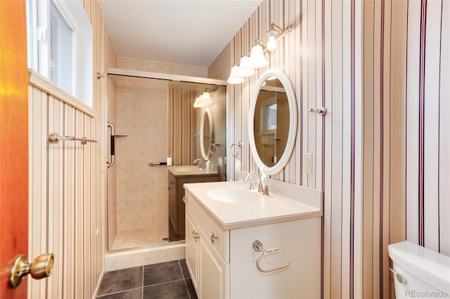 bathroom featuring tile patterned flooring, vanity, a shower with shower door, and toilet