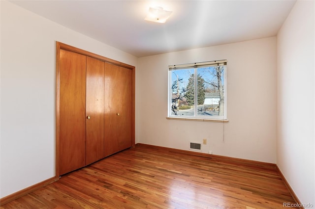 unfurnished bedroom with light wood-type flooring and a closet