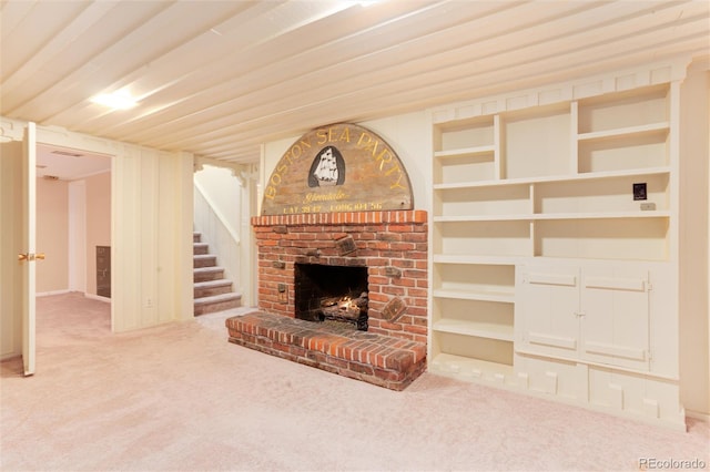 unfurnished living room featuring a brick fireplace, carpet flooring, and built in shelves