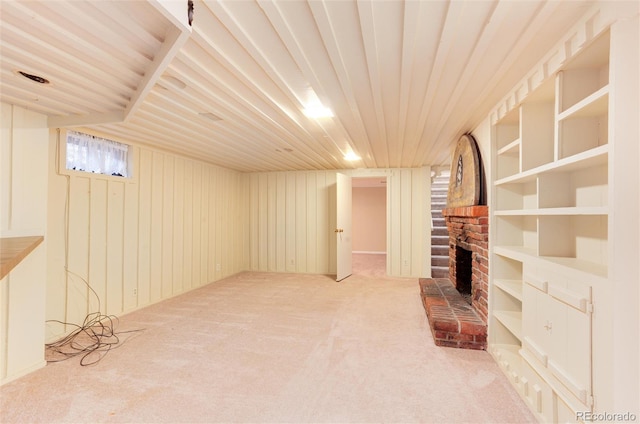 basement featuring built in features, wooden walls, carpet floors, a fireplace, and wooden ceiling