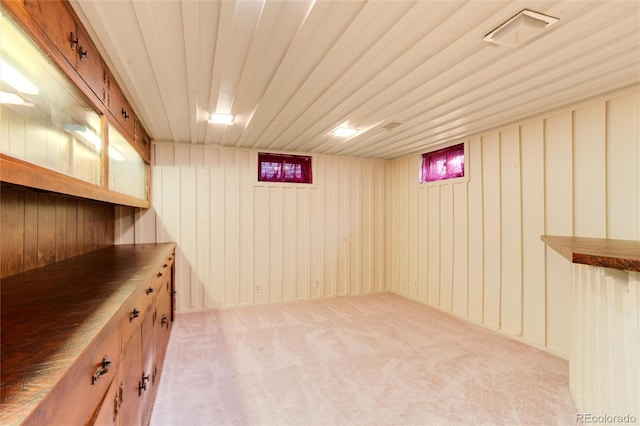 basement featuring light colored carpet and wood walls