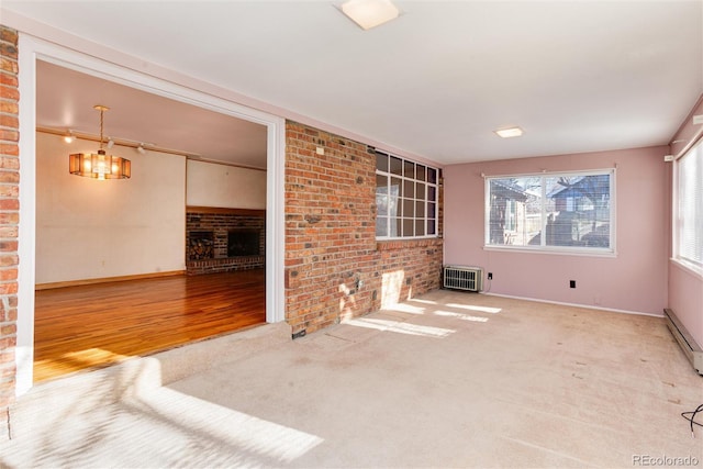 unfurnished living room featuring heating unit, a fireplace, carpet flooring, a chandelier, and baseboard heating