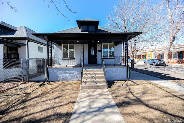 view of front of property featuring covered porch, brick siding, fence, and a gate