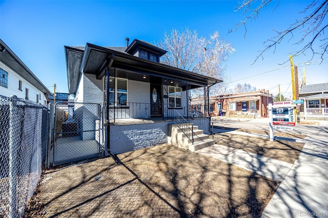 view of front of home with covered porch, brick siding, fence, and a gate