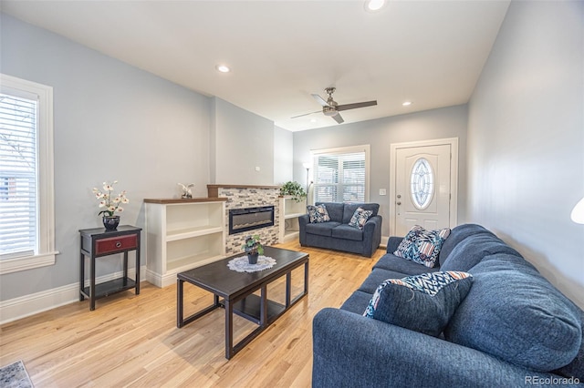 living room with a tile fireplace, light wood-style flooring, baseboards, and recessed lighting